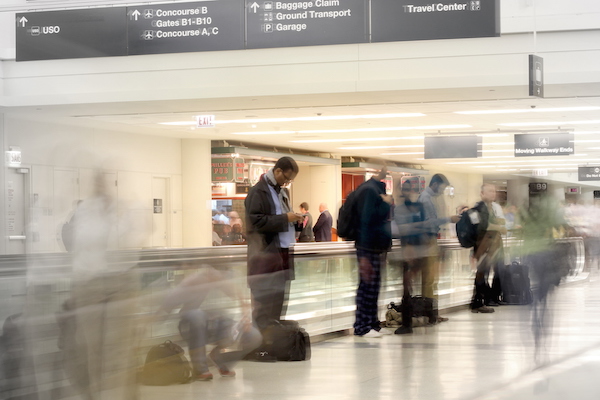 Gentleman with sensory impairment is standing in the airport terminal, his surroundings seem a blur